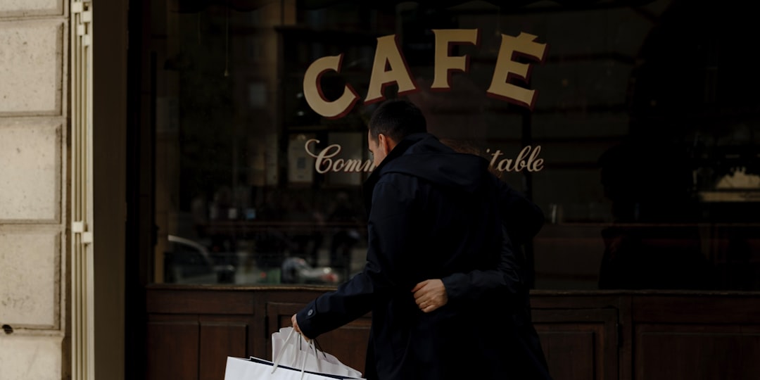 A person looking at a cafe menu board while holding a coat and scarf. Person looking at a coffee shop menu board while holding a winter coat and scarf
